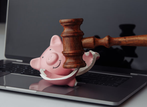 Broken piggy bank and wooden gavel on laptop's keyboard. Busines