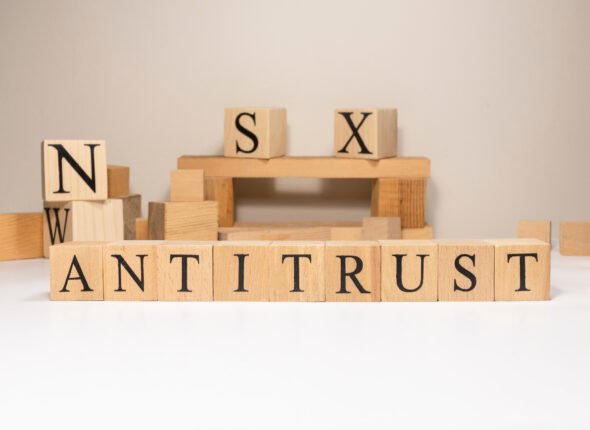Antitrust. The term economy and trade. Written in wooden cubes.