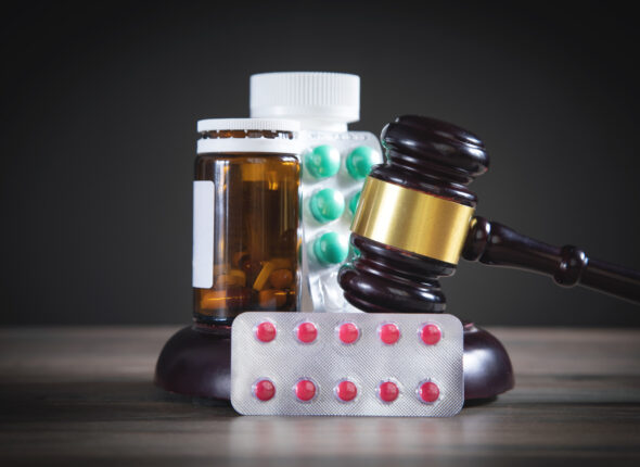 Judge gavel with pills on the wooden table.