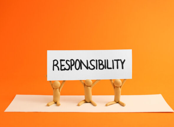 Three plasticine human figures holding card with word Responsibi