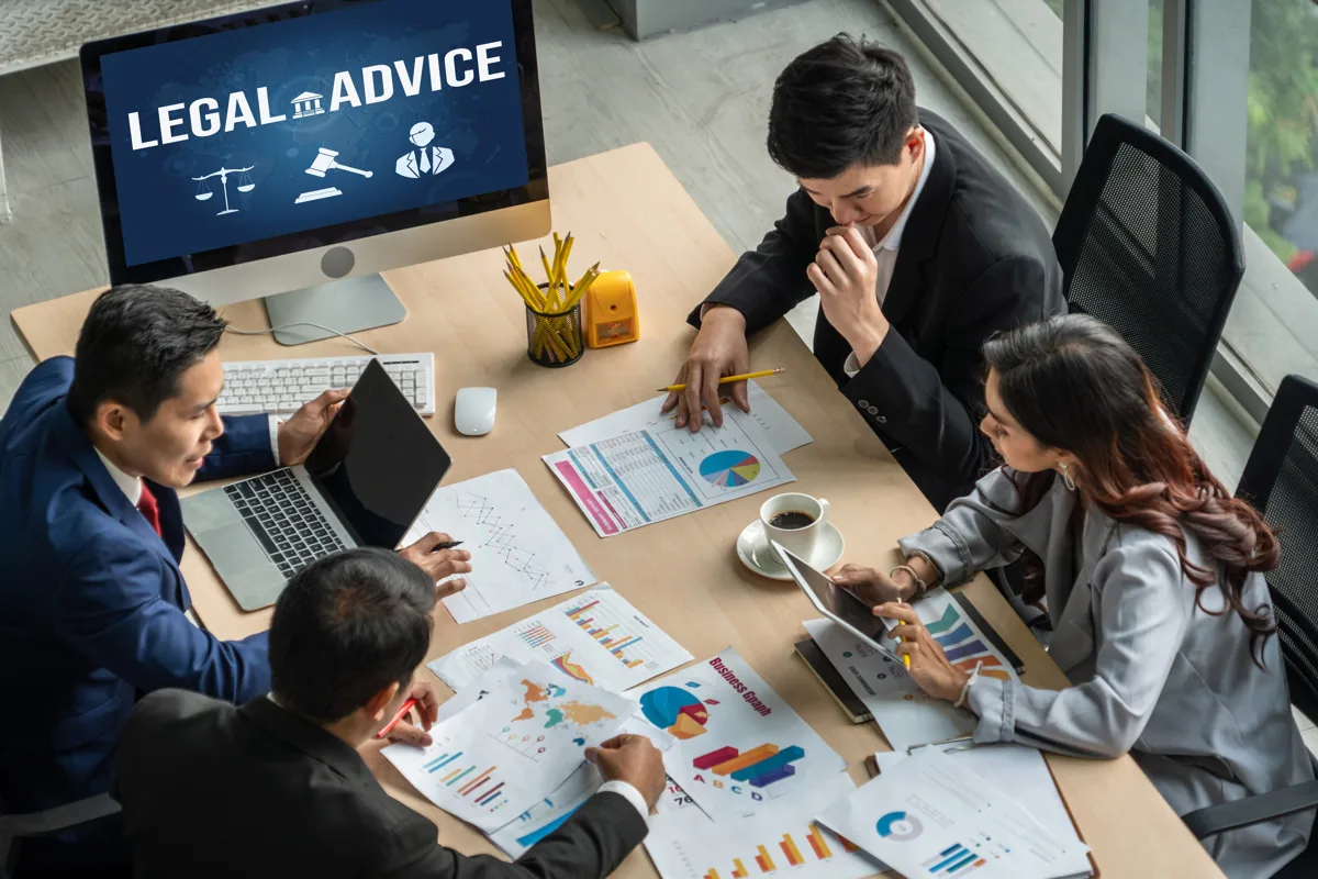 Legal professionals reviewing documents around a desk, illustrating a law firm client onboarding program.